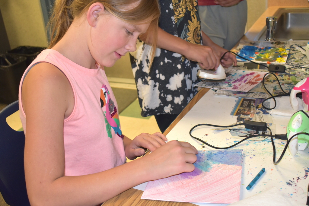 Students ironing art work with crayons